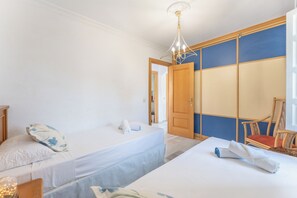 Ein Hotelzimmer mit zwei Einzelbetten, einer Holztür, einem großen Spiegel und einem Stuhl.