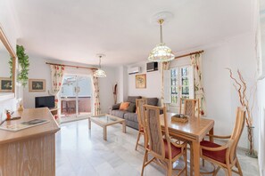 A modern living room with a sofa, dining table, chairs, and a balcony with a view. - Coastal 2‑Bed Retreat Filled with Spanish Charm - Pass the Keys (Benalmadena)