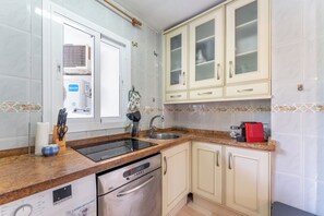A kitchen with a dishwasher, stove, and a red coffee maker. - Coastal 2‑Bed Retreat Filled with Spanish Charm - Pass the Keys (Benalmadena)