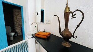 A bathroom with a sink, mirror, and a decorative metal vase on the counter. - Maisonette with Rooftop Terrace at Bab Souk – AC, WiFi & Medina Views (Chefchaouen)