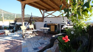 An outdoor patio with a wooden pergola, a patterned floor, and a table with chairs. - Cedar, Lime & Light – A Boutique Auberge at Chefchaouen's Historic Gate (Chefchaouen)