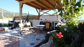 Un pati exterior amb una pergola de fusta, un paviment amb dibuixos i una taula amb cadires.
