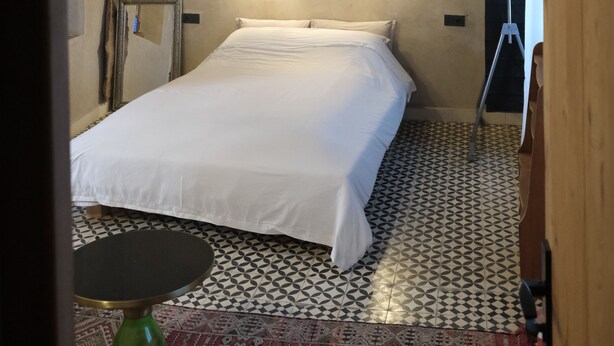 A bedroom with a bed, two wall-mounted lights, a patterned floor, and a wooden door. - Cedar, Lime & Light – A Boutique Auberge at Chefchaouen's Historic Gate (Chefchaouen)