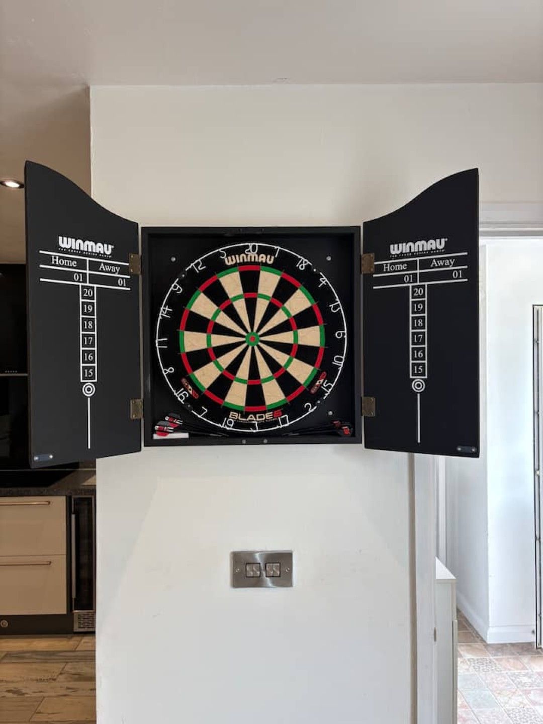 A dartboard mounted on a wall with a scorecard on either side.