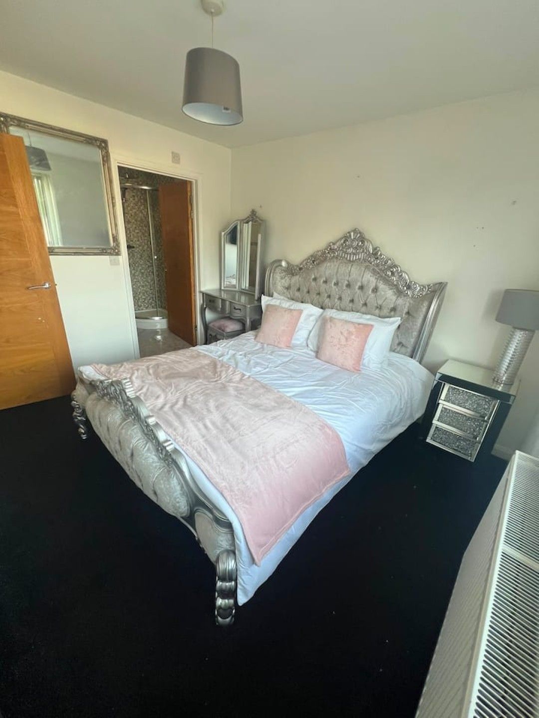 A bedroom with a large bed, a dresser, a mirror, and a nightstand.