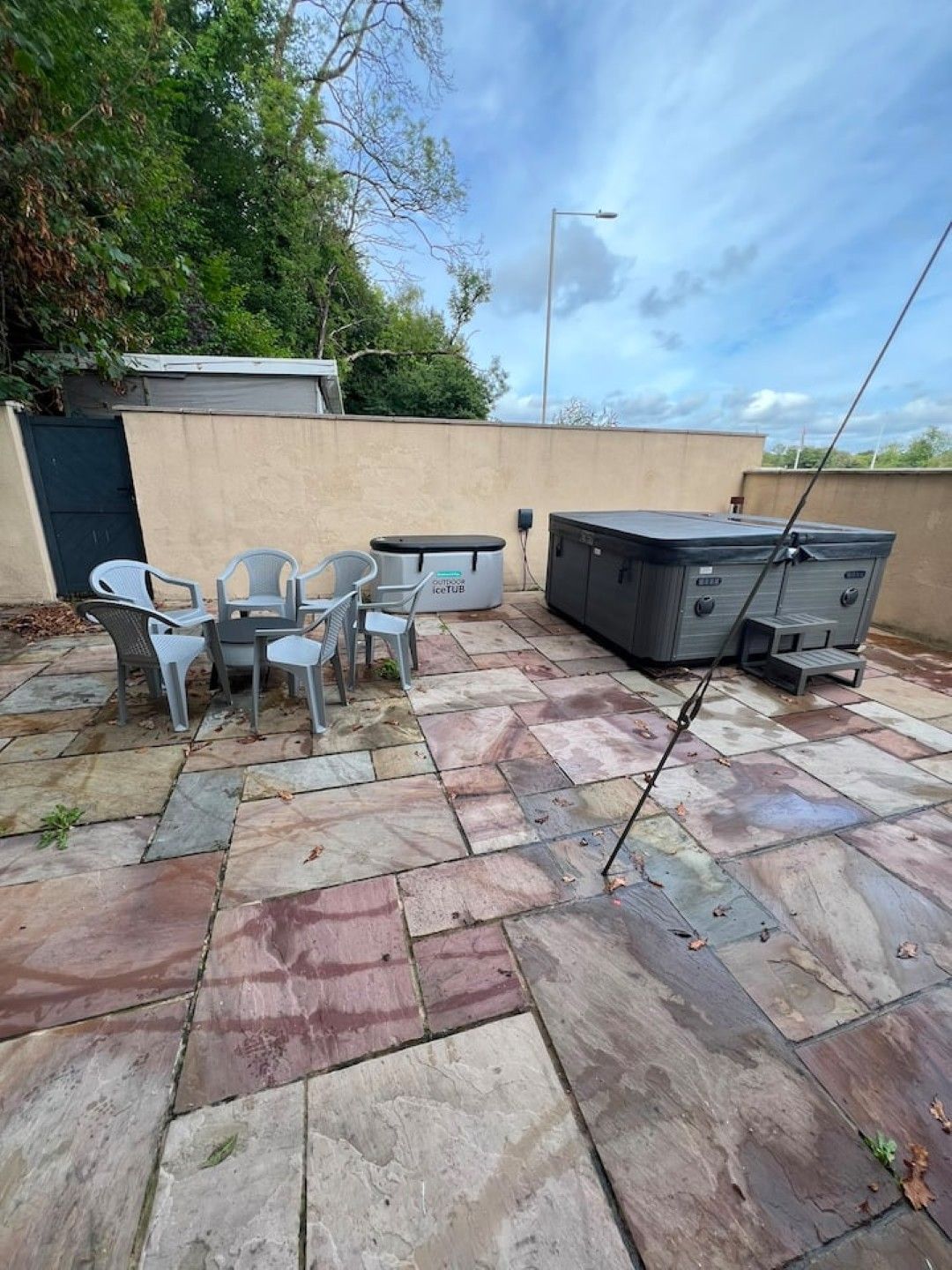 An outdoor patio with stone flooring, a hot tub, and a seating area with chairs and a table.