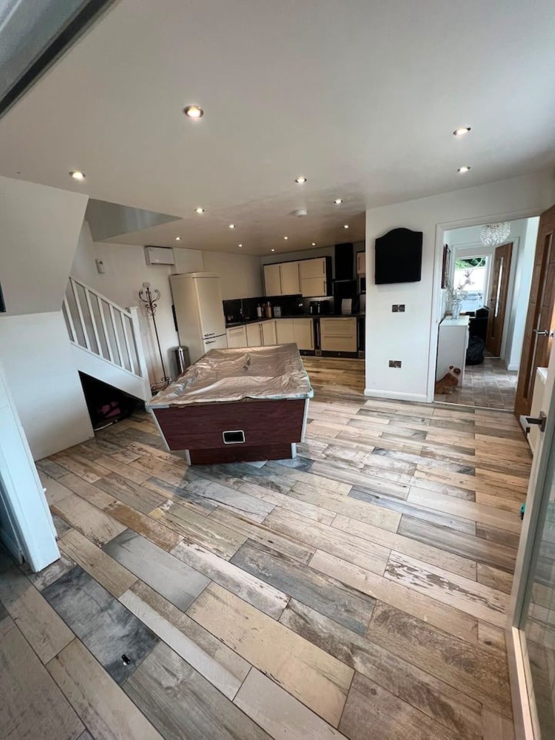 A spacious kitchen with modern appliances and a herringbone wood floor.