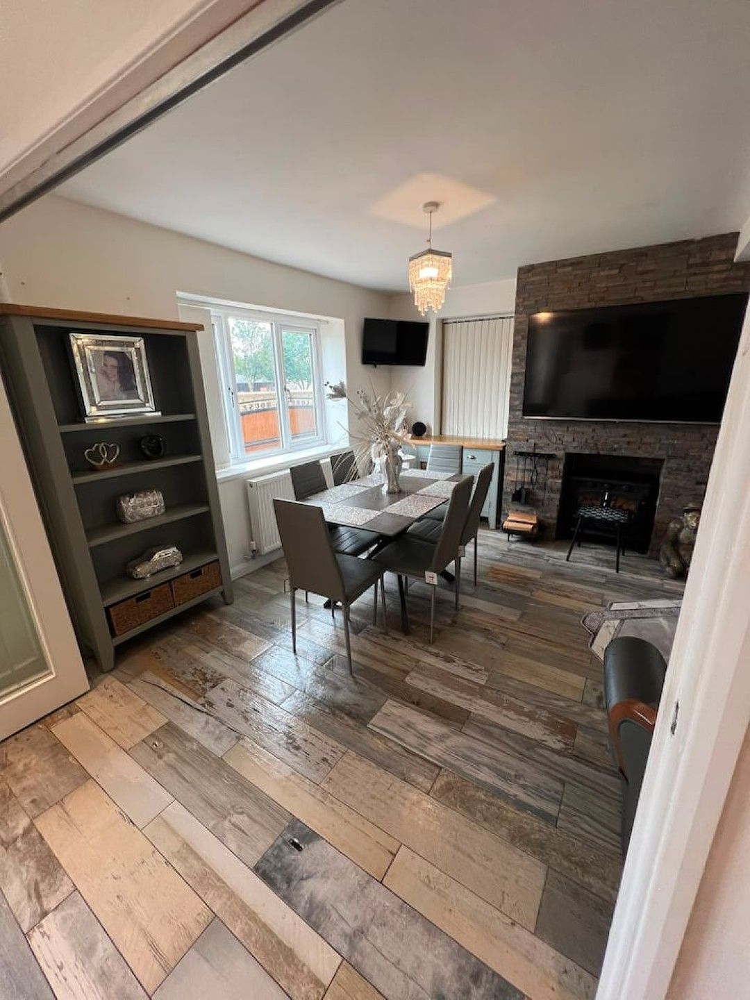 A dining area with a table and chairs, a fireplace, and a television mounted on the wall.