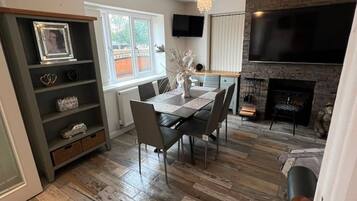 A dining area with a table and chairs, a fireplace, and a television mounted on the wall.