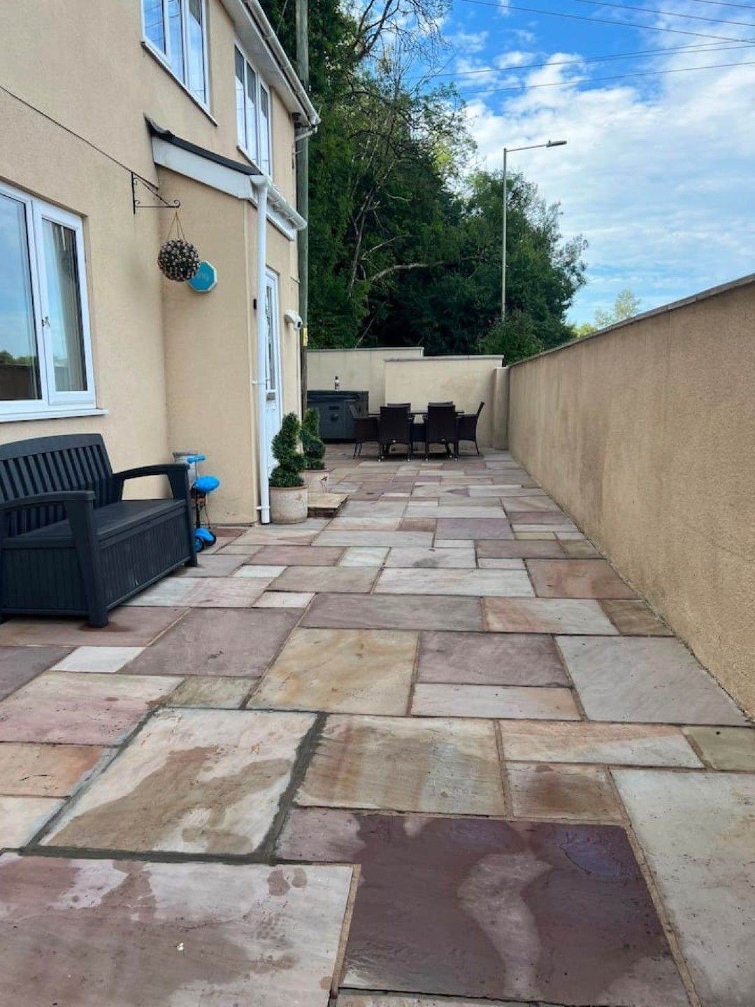 A patio with stone flooring, outdoor furniture, and a view of a residential building.