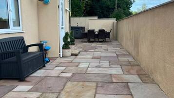 A patio with stone flooring, outdoor furniture, and a view of a residential building.