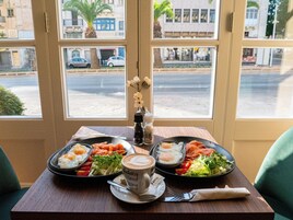 Una mesa con un desayuno que incluye huevos, verduras y salmón, acompañado de una taza de café.