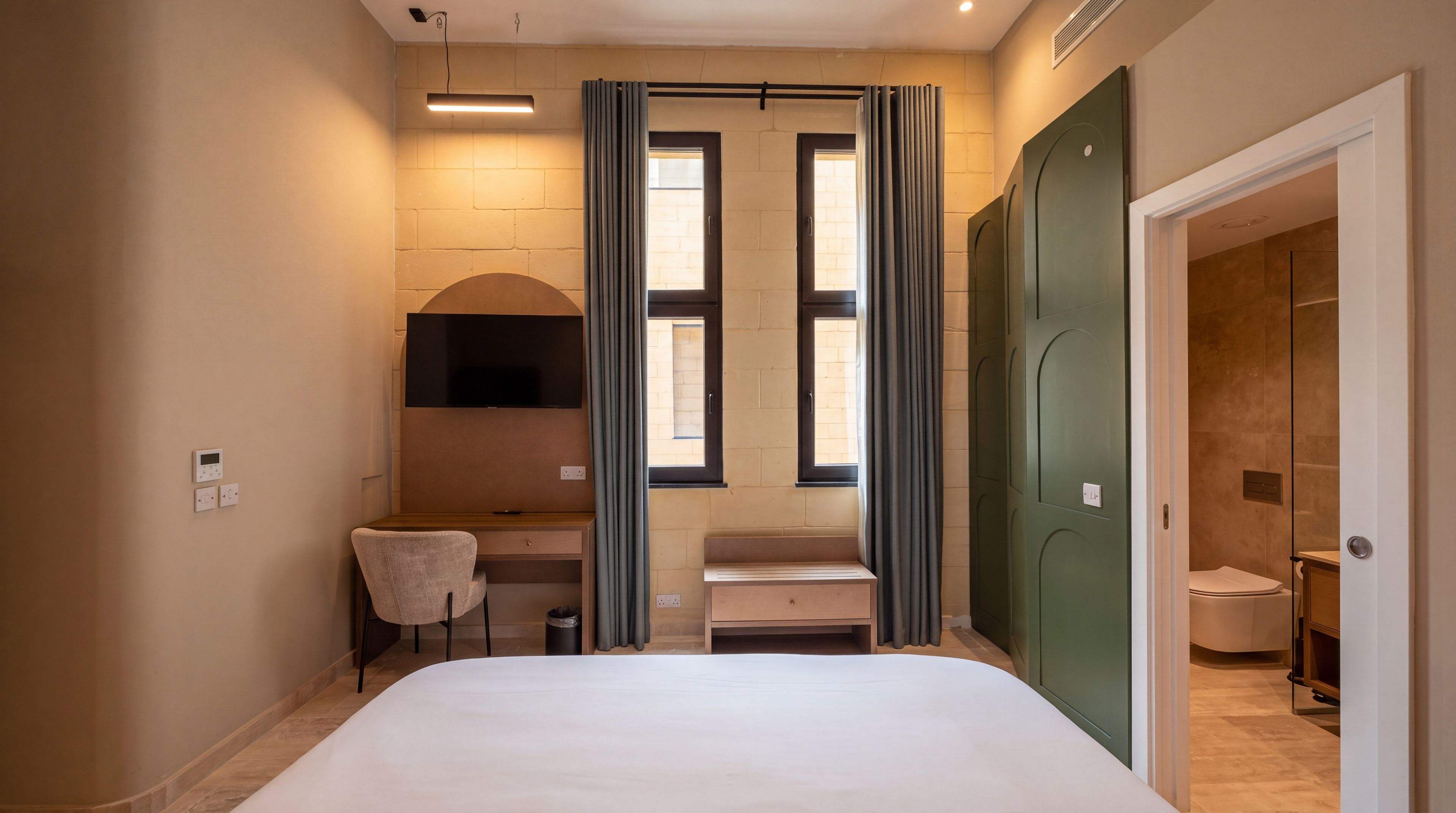 Une chambre d’hôtel comprenant un lit, un bureau, une chaise, une télévision et une armoire.