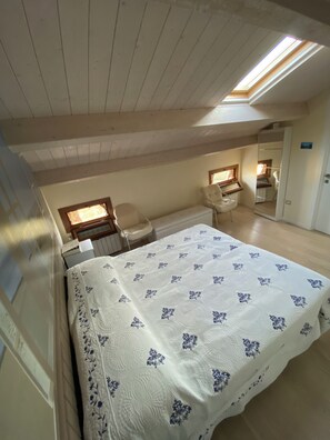 A bedroom with a skylight, a bed with a floral bedspread, a desk, and a chair. - Fairmont Residence Elisabetta by Ca-sa Check (Chioggia)