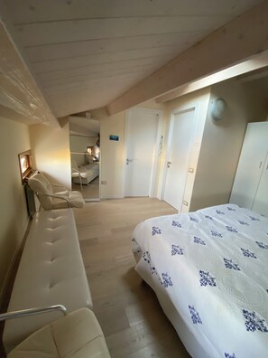 Een slaapkamer met een bed, een stoel, een spiegel en een deur.