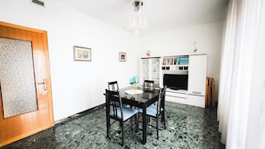 A dining area with a black table, four chairs, a chandelier, a bookshelf, and a door. - Canal Bellavista by Ca-sa Check (Chioggia)