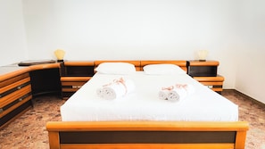 A neatly made bed with two rolled towels, a wooden headboard, and a nightstand with a lamp. - Canal Bellavista by Ca-sa Check (Chioggia)