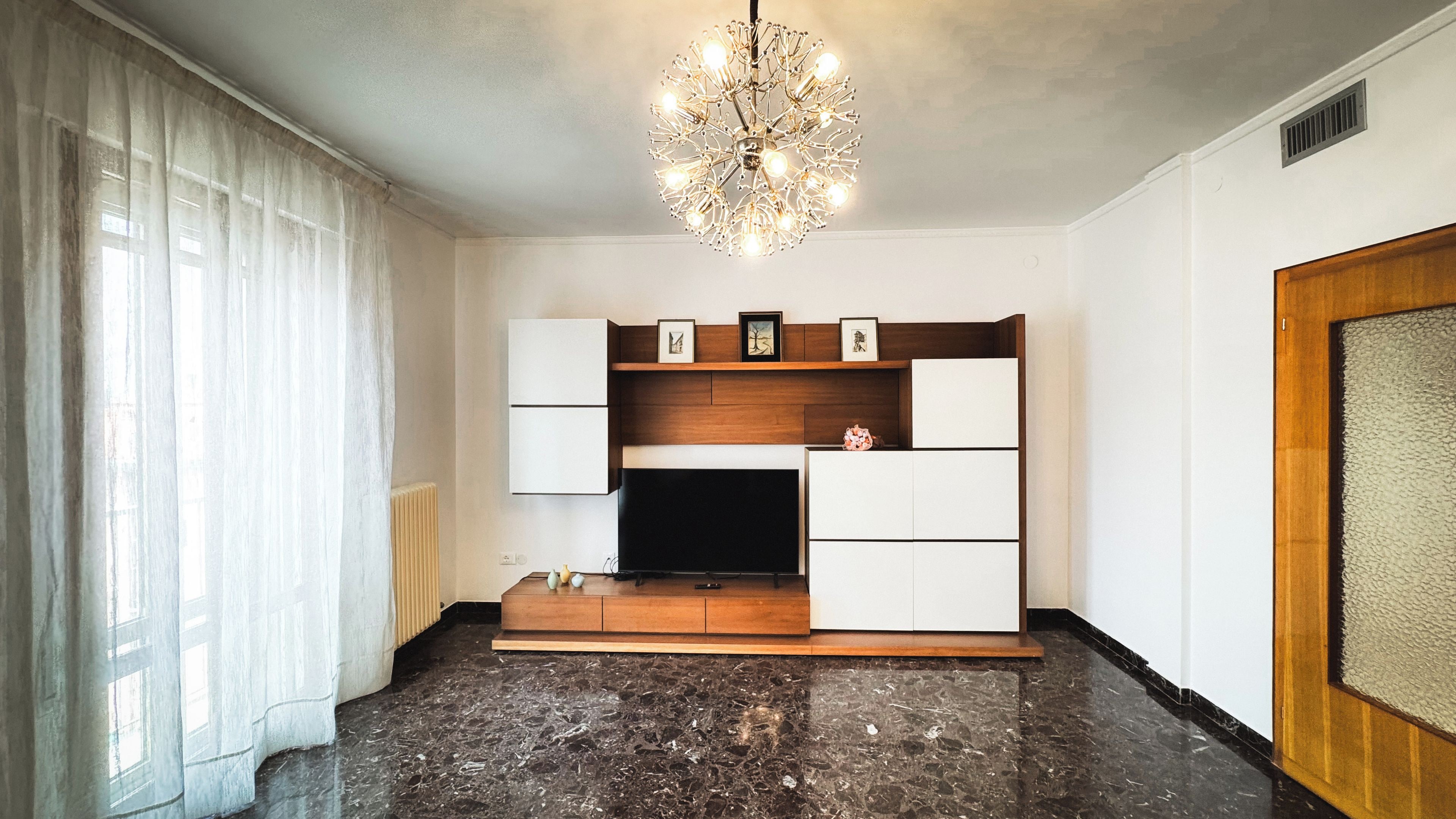 A living room with a modern fireplace, built-in TV, and a chandelier.