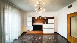 Un salon doté d’une cheminée moderne, d’un téléviseur encastré et d’un lustre.