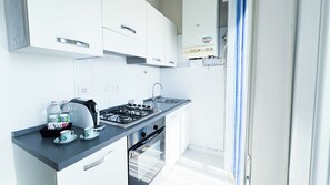 Uma cozinha moderna com armários brancos, fogão a gás, pia e forno embutido.