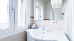 A bathroom with a white sink, a mirror, and a window with a view. - Farmont Residence Alice by Ca-sa Check (Chioggia)