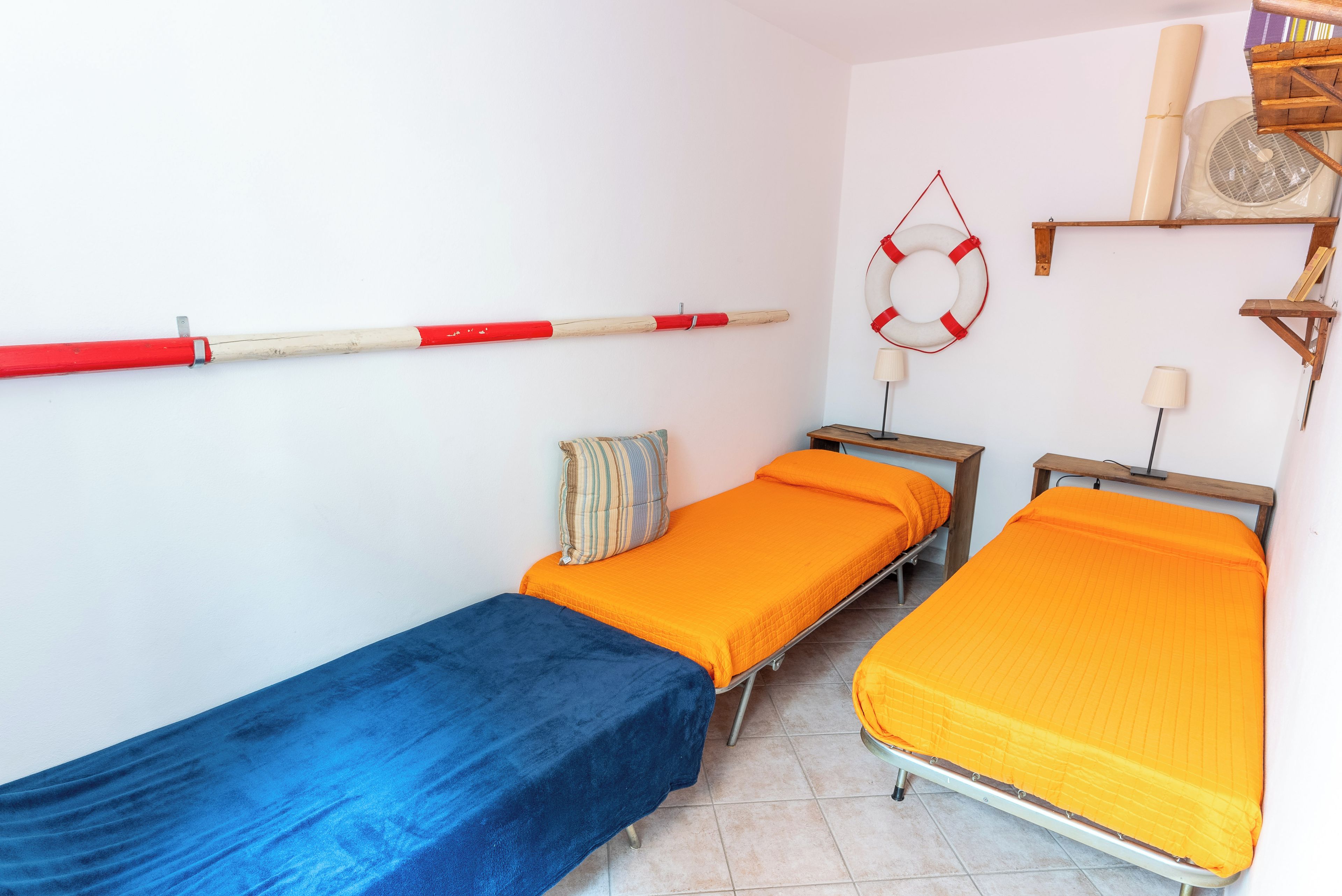 A room with two single beds, a blue bedspread, and an orange bedspread.