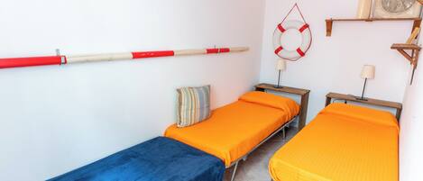 A room with two single beds, a blue bedspread, and an orange bedspread.