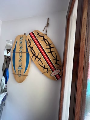 Due tavole da surf in legno con decorazioni e scritte, appese a una parete.