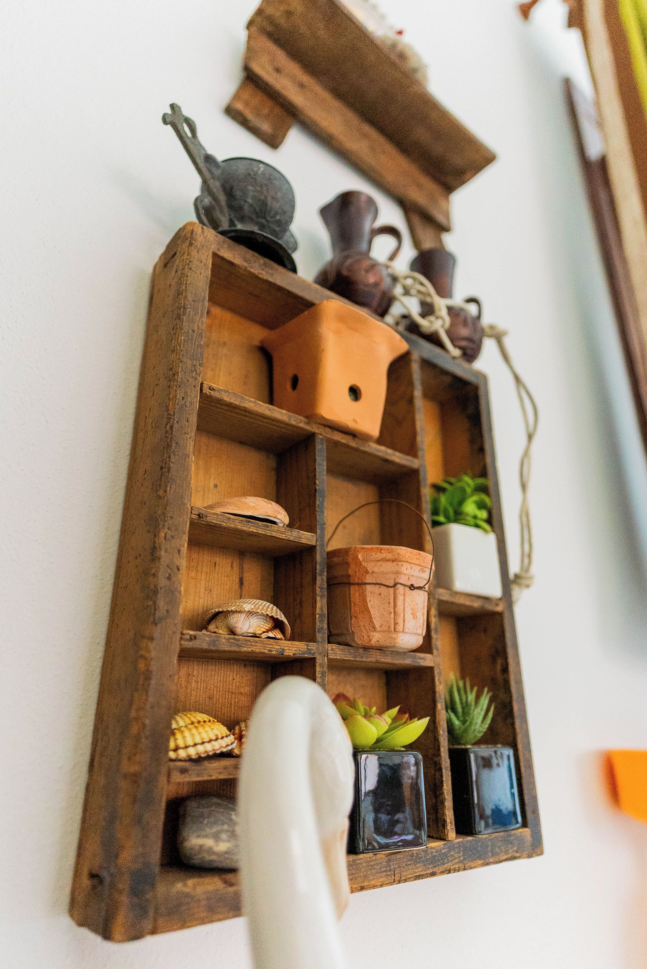 Una estantería de madera con varios objetos, incluyendo una olla, un recipiente pequeño y una planta.