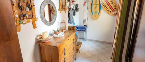 A room with a wooden dresser, a mirror, and various decorative items including seashells and a surfboard.