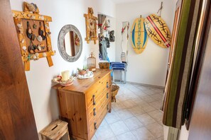 Una stanza arredata con un comò in legno, uno specchio e diversi oggetti decorativi tra cui conchiglie e una tavola da surf.