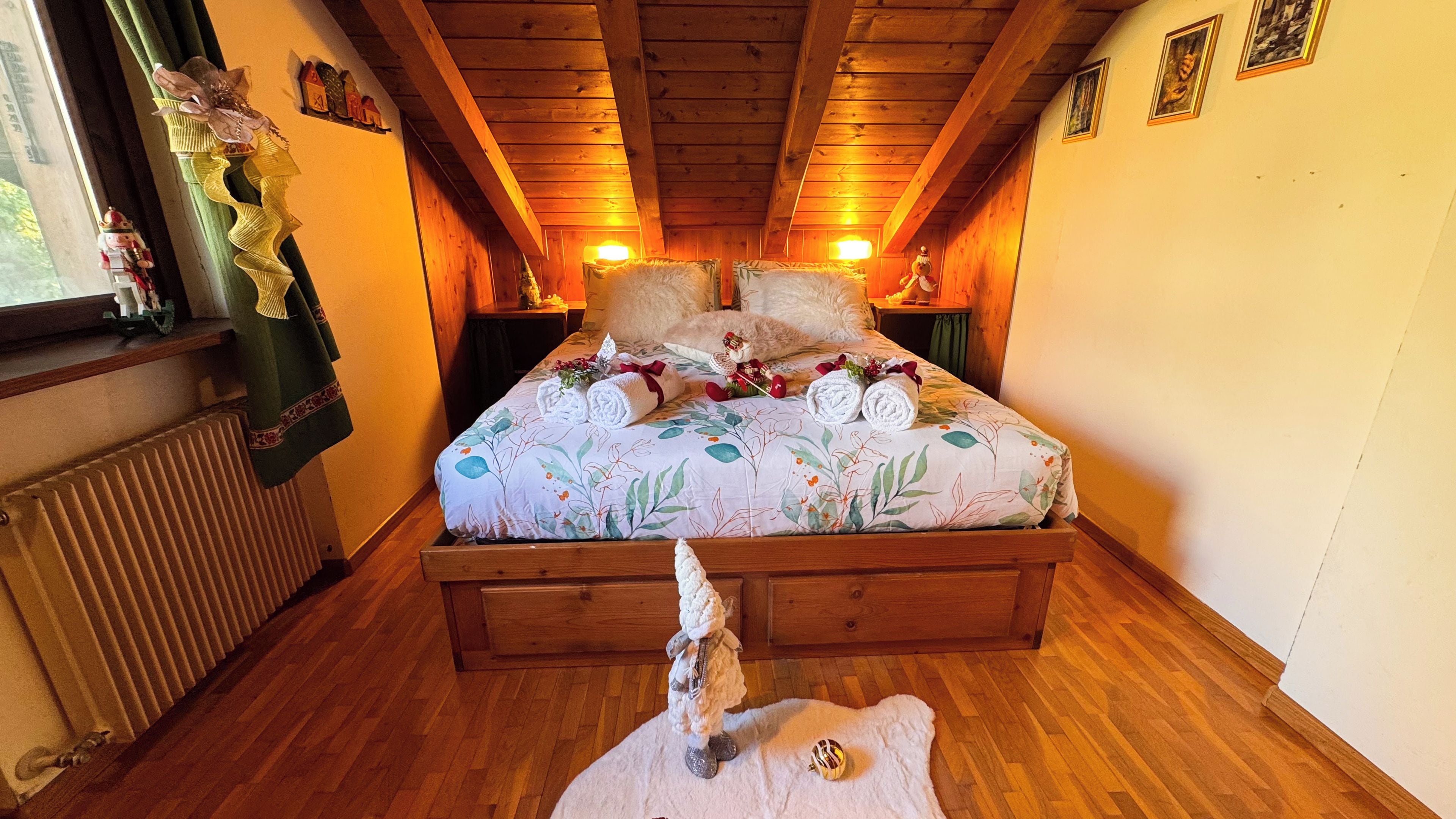 Un dormitorio acogedor con techo de madera, edredón estampado con flores y una alfombra mullida.