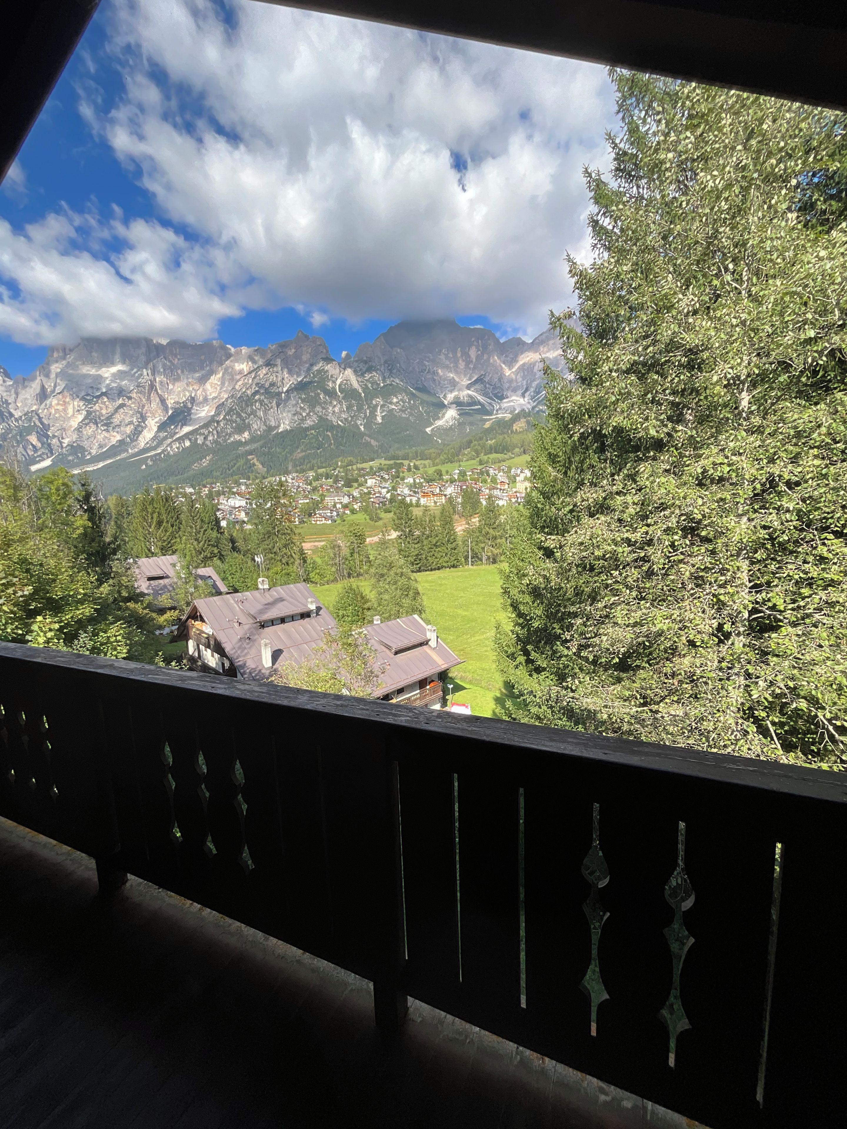 Een berglandschap met een dorp eronder, gezien vanaf een balkon met een hekwerk.