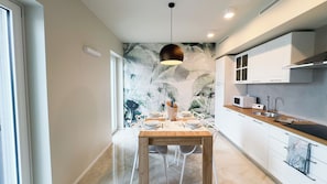 Una cocina moderna con armarios blancos, encimera de madera y un comedor con mesa preparada para cuatro.
