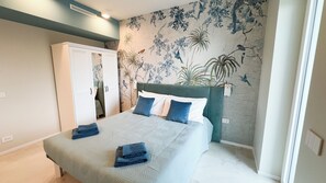 Quarto com cama, guarda-roupa e parede com mural de tema natural.