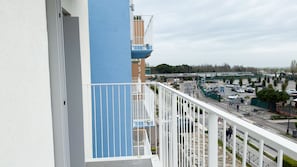 Un balcón con vistas a un estacionamiento y un edificio con la palabra 'JOSE' en su fachada.