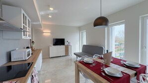 A modern kitchen with a microwave, a wooden countertop, and a dining area with a table set for two. - Farmont Seafront Flamingo Suite by Ca-sa Check (Chioggia)