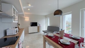 A modern kitchen with a microwave, a wooden countertop, and a dining area with a table set for two. - Farmont Seafront Flamingo Suite by Ca-sa Check (Chioggia)
