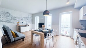 A modern living space with a dining area, a kitchen, and a large window overlooking a marina. - Farmont Seafront Venice Suite by Ca-sa Check (Chioggia)