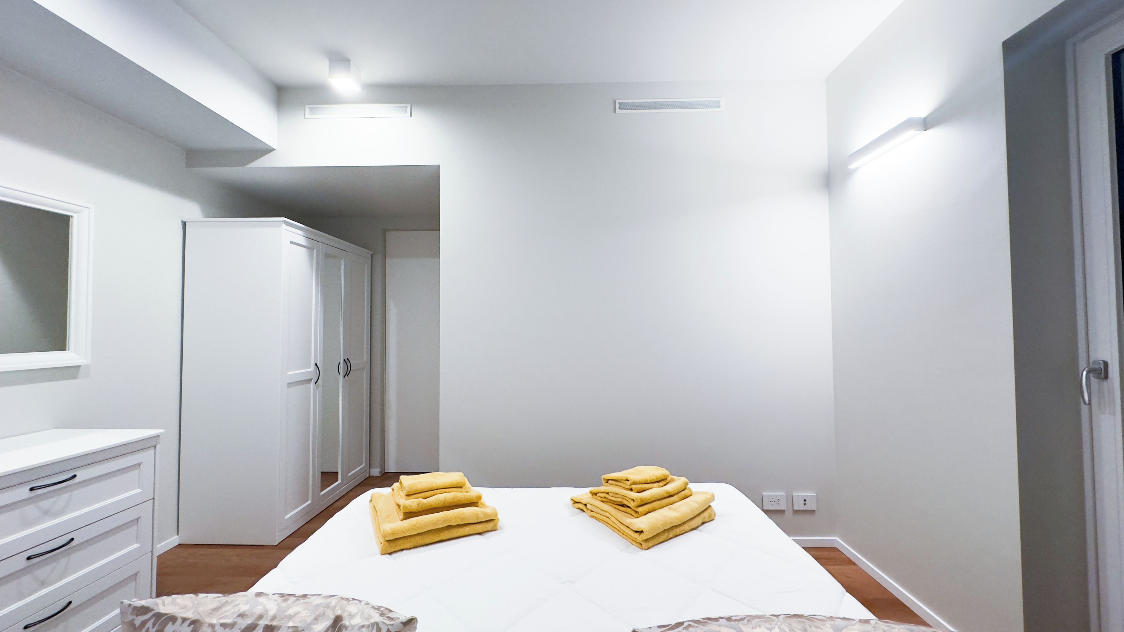 A hotel room with a bed, a wardrobe, a mirror, and a door.