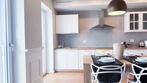 A modern kitchen with white cabinets, a central island with seating, and a pendant light. - Farmont Seafront Venice Suite by Ca-sa Check (Chioggia)