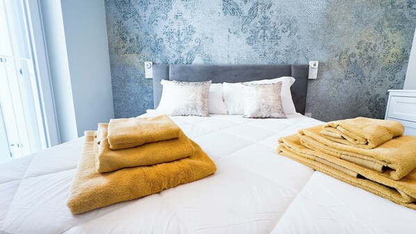 Una habitación de hotel con cama, almohadas y toallas dobladas.