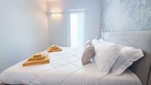 Una habitación de hotel con cama, almohadas y una ventana.