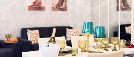 A dining table set with wine glasses, a bottle of champagne, and a white pitcher.