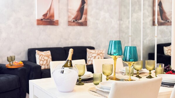 Uma mesa de jantar posta com taças de vinho, uma garrafa de champanhe e um jarro branco.
