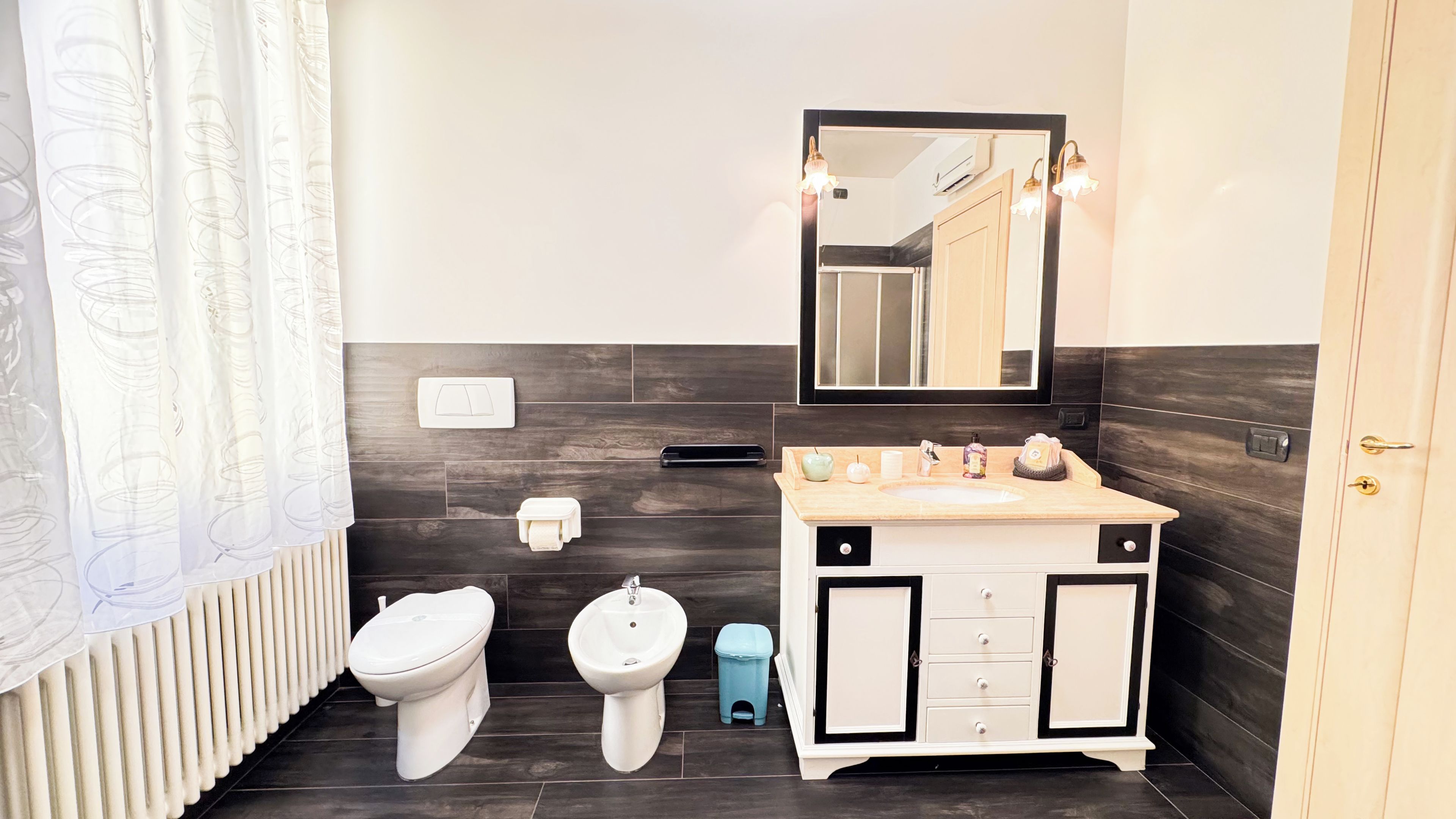 A modern bathroom with a toilet, bidet, sink, and mirror.