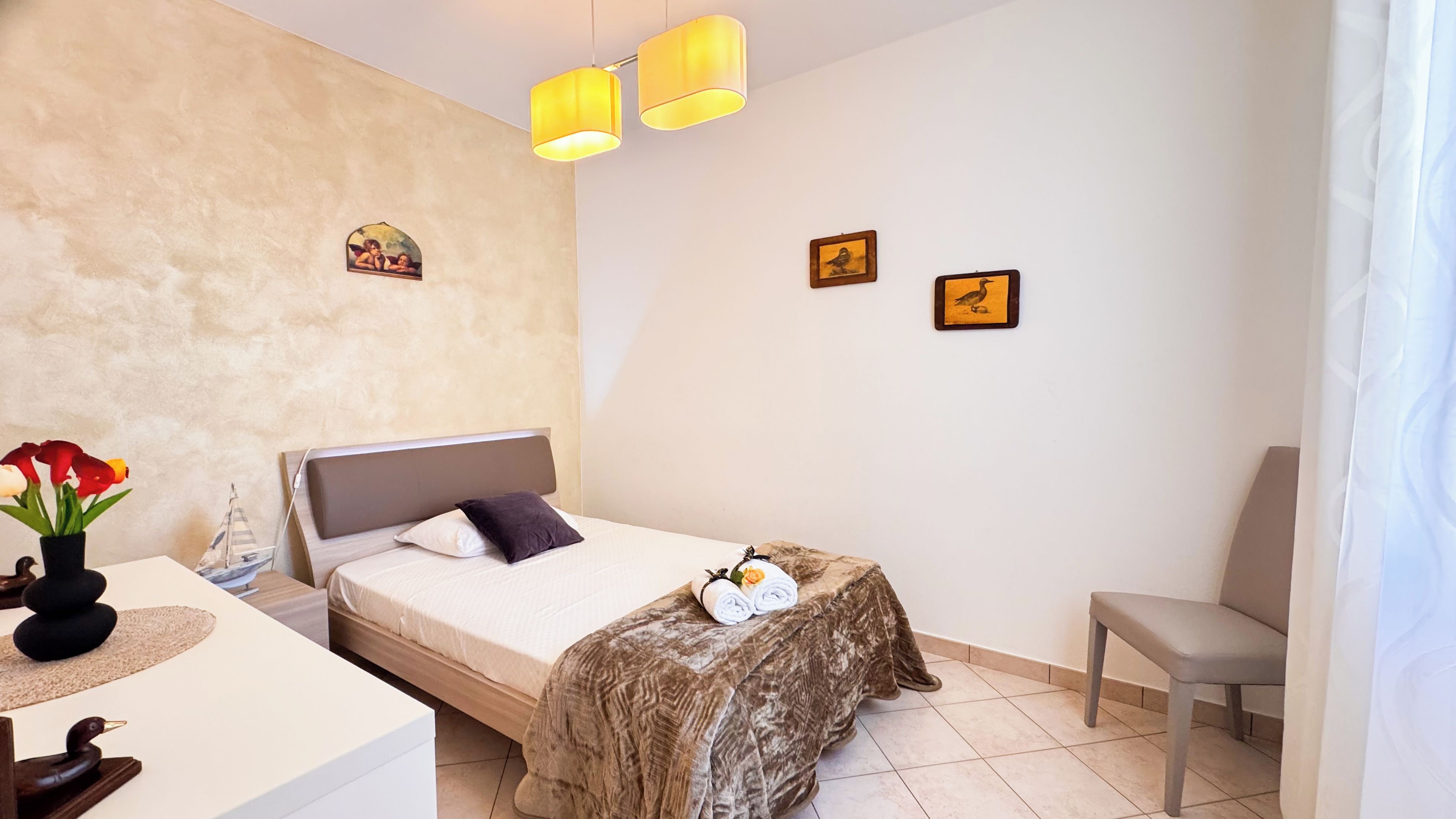 A bedroom with a bed, bedside table, lamp, and a chair.