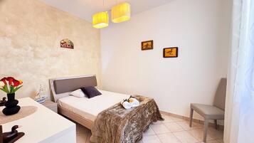A bedroom with a bed, bedside table, lamp, and a chair.