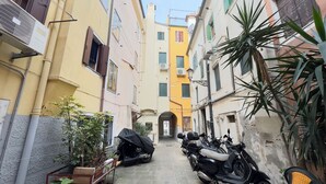 A narrow alley with buildings on either side, a covered motorcycle, and a scooter parked on the right. - Novo Taccheo by Ca-sa Check (Chioggia)