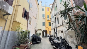 A narrow alley with buildings on either side, a covered motorcycle, and a scooter parked on the right. - Novo Taccheo by Ca-sa Check (Chioggia)